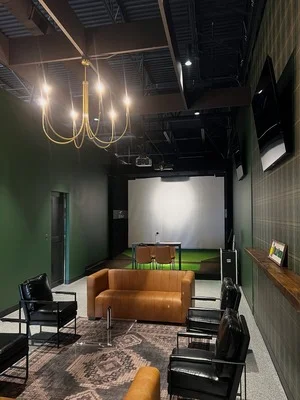 Commercial interior with green accent wall, black ceiling, brass pendant lighting, and neutral painted surfaces