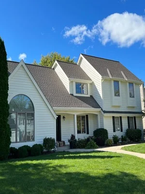 White painted two-story colonial home with gray roof, black shutters and trim, manicured landscaping