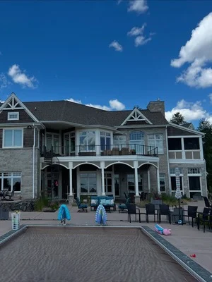 Two-story house with gray exterior paint, white trim, and dark roof against blue sky