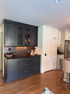 Charcoal gray painted kitchen cabinets with glass doors and brick backsplash accent wall