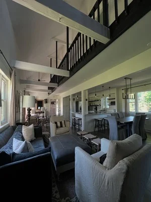 Interior living room with sage green walls, white ceiling, and dark stair railings
